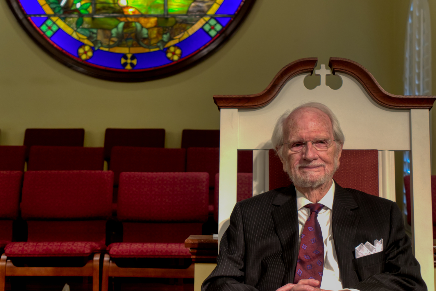 Dr. Jimmy Latimer sitting in front of stained glass